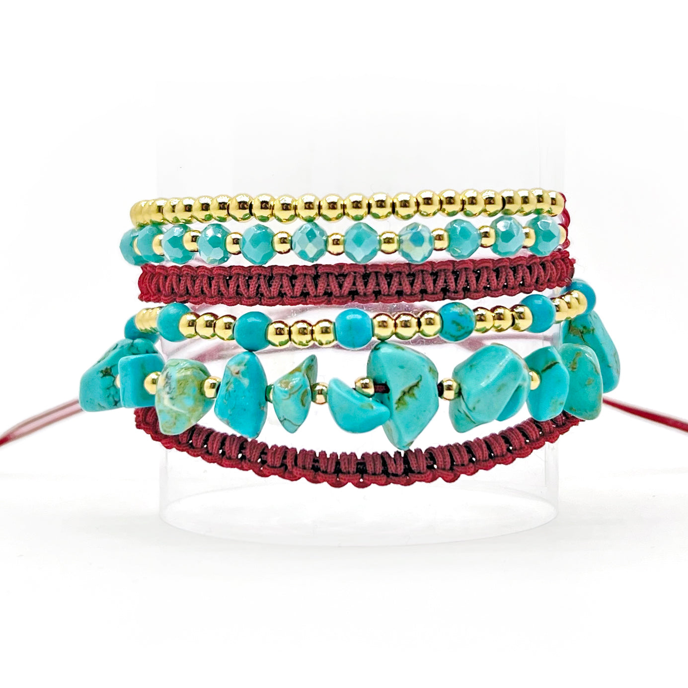 A 6in1 wrap bracelet featuring gold plated beads, turquoise beads, and a red burgundy thread. The bracelet is wrapped around a wrist multiple times, creating a layered and textured appearance. The gold beads add sophistication while the turquoise beads bring vibrancy to the design. Suitable for any occasion, this unique bracelet is a great addition to any jewelry collection.